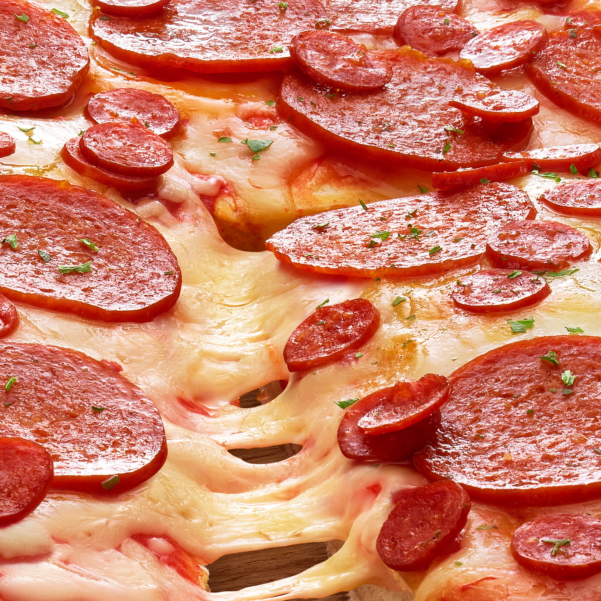 Extreme close-up of a pepperoni pizza with melted cheese pulls, showcasing vibrant toppings and gooey cheese stretching from the slice.